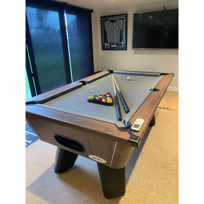 Pool table with balls and cues in a room with a television and framed picture on the wall.