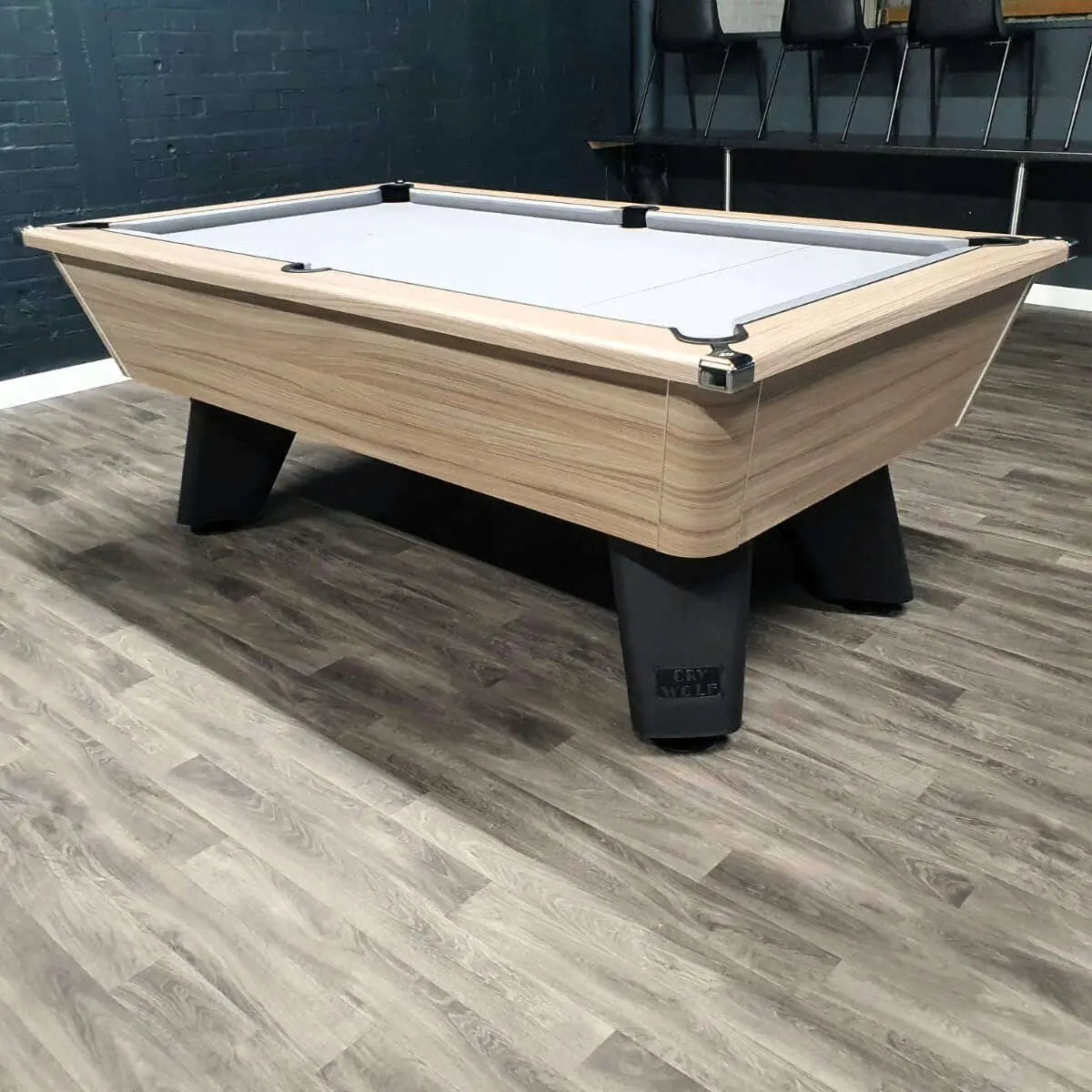 Pool table with wooden finish and black legs on a wooden floor.
