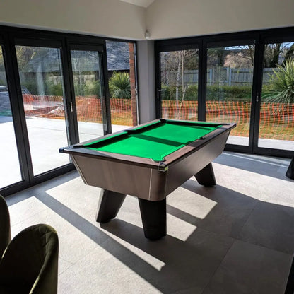 Pool table in a room with large windows showing an outdoor view.
