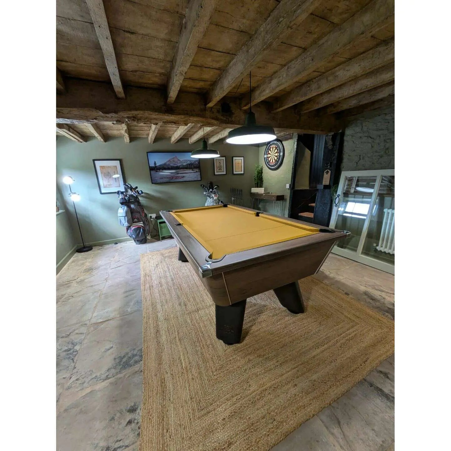 Game room with pool table, dartboard, and framed pictures on a wooden floor.