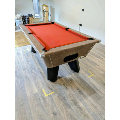Pool table with red felt surface in a room with wooden flooring.