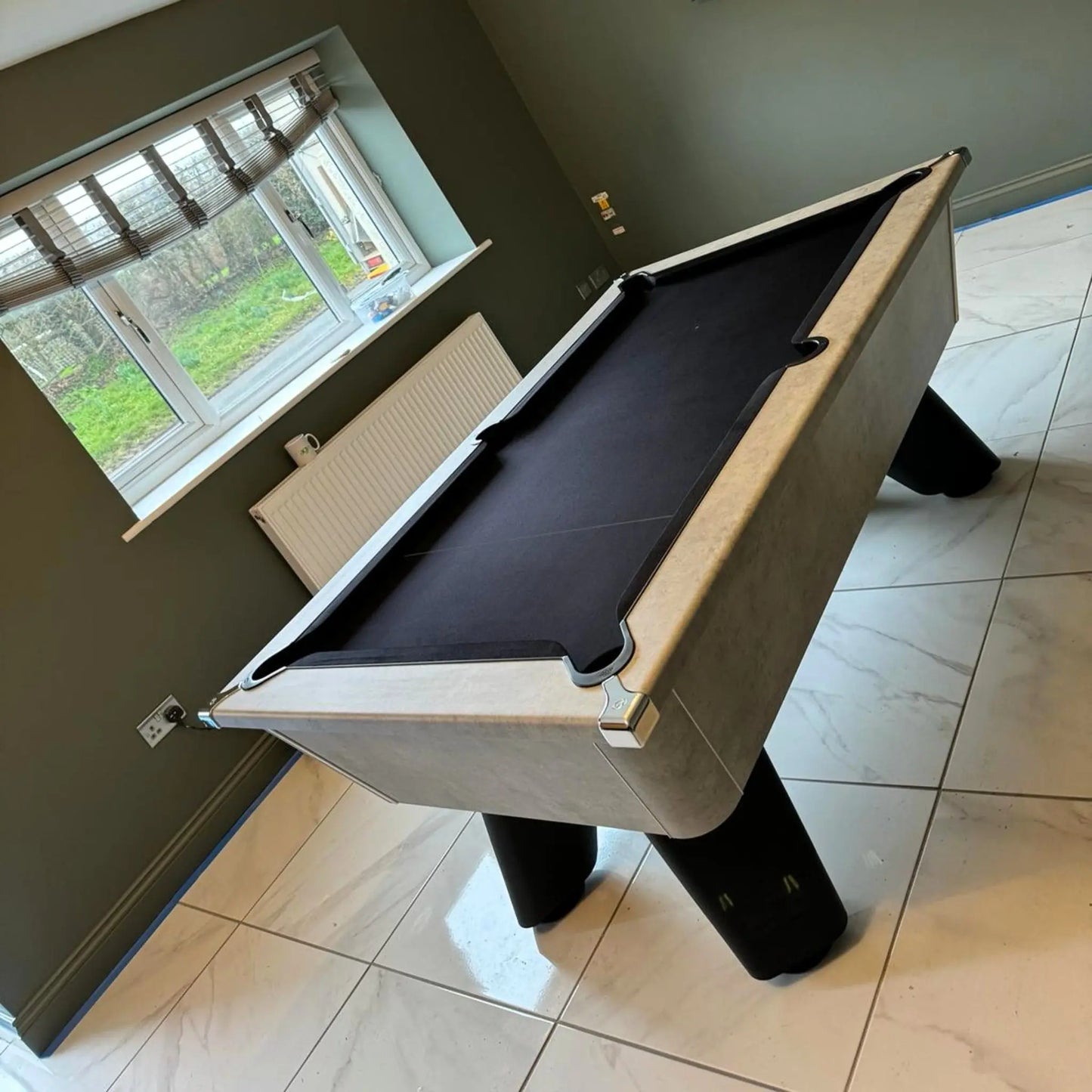 Pool table in a room with a window and tiled floor