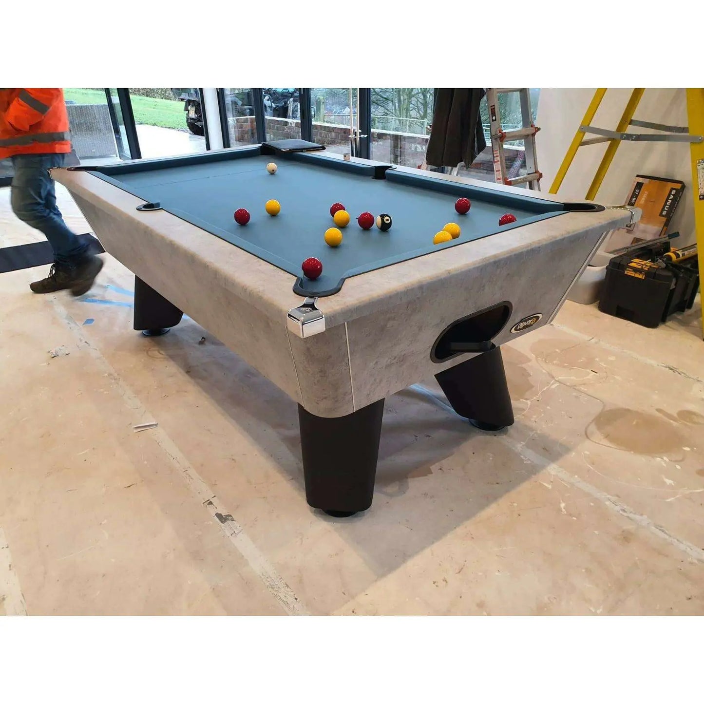 Pool table with scattered balls in a room with construction elements