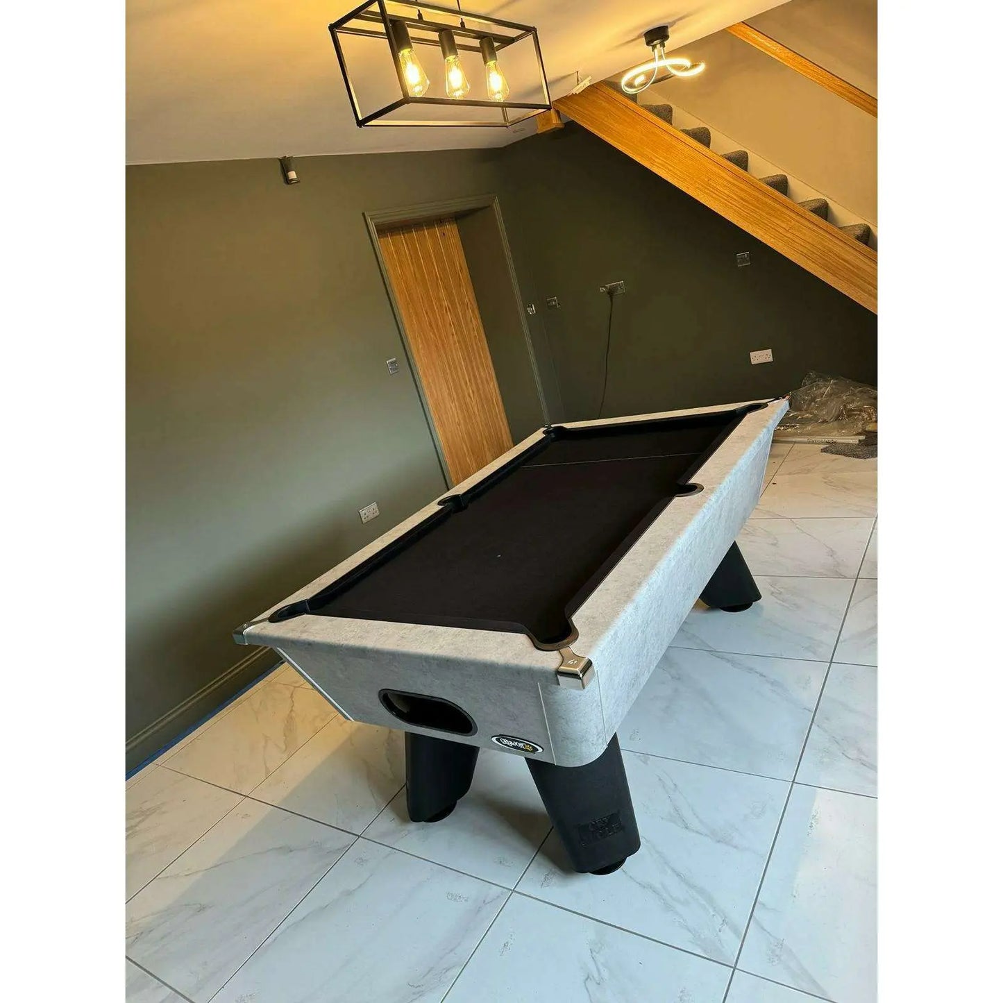 Pool table in a room with a staircase and light fixture.