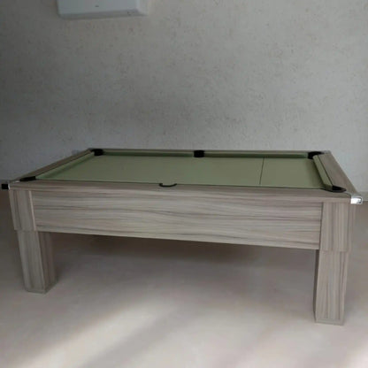 Pool table with green felt surface and wooden frame against a plain wall.