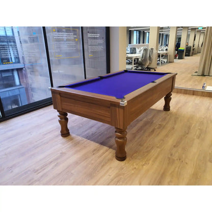 A wooden pool table with a vibrant purple felt playing surface, positioned on a light wood floor inside an office environment.