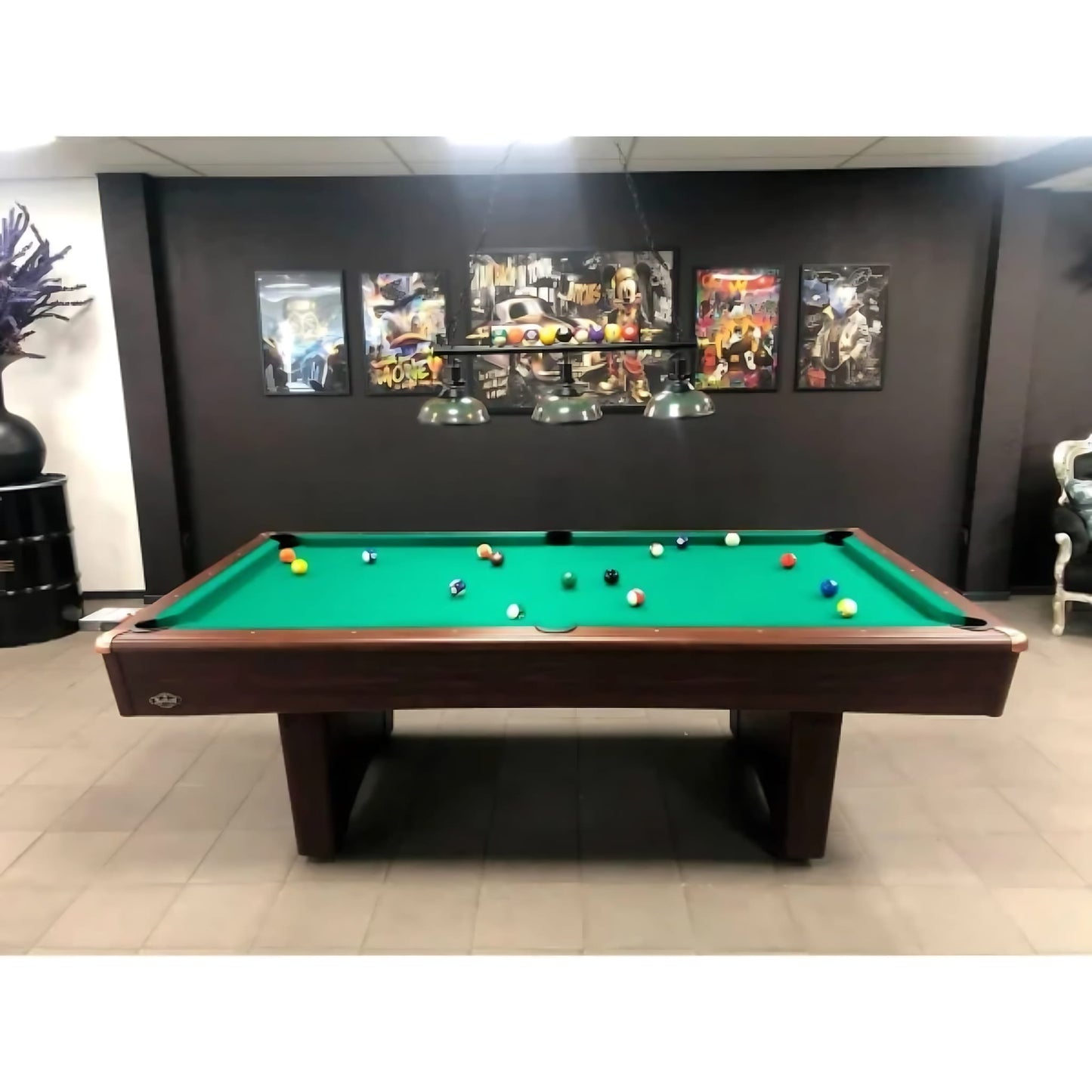 Pool table with colorful balls in a room with framed pictures on the wall.