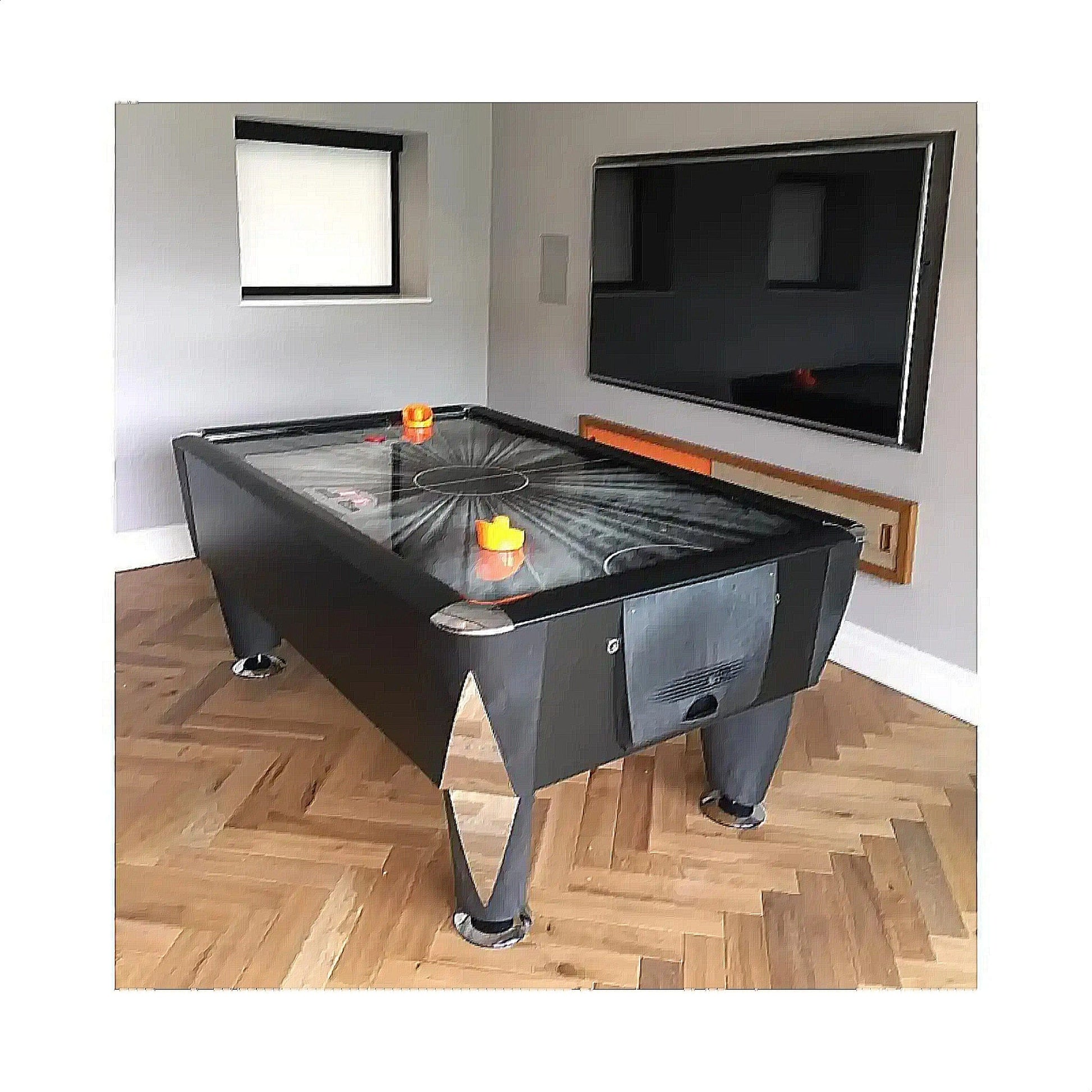 Air hockey table in a room with a television mounted on the wall.
